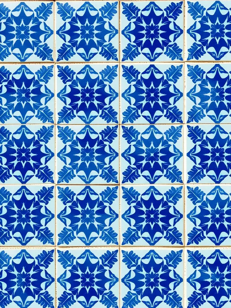 A close-up shot of a large, intricately patterned ceramic floor tile, showcasing its detailed design and smooth, glossy finish, set in a modern living room.